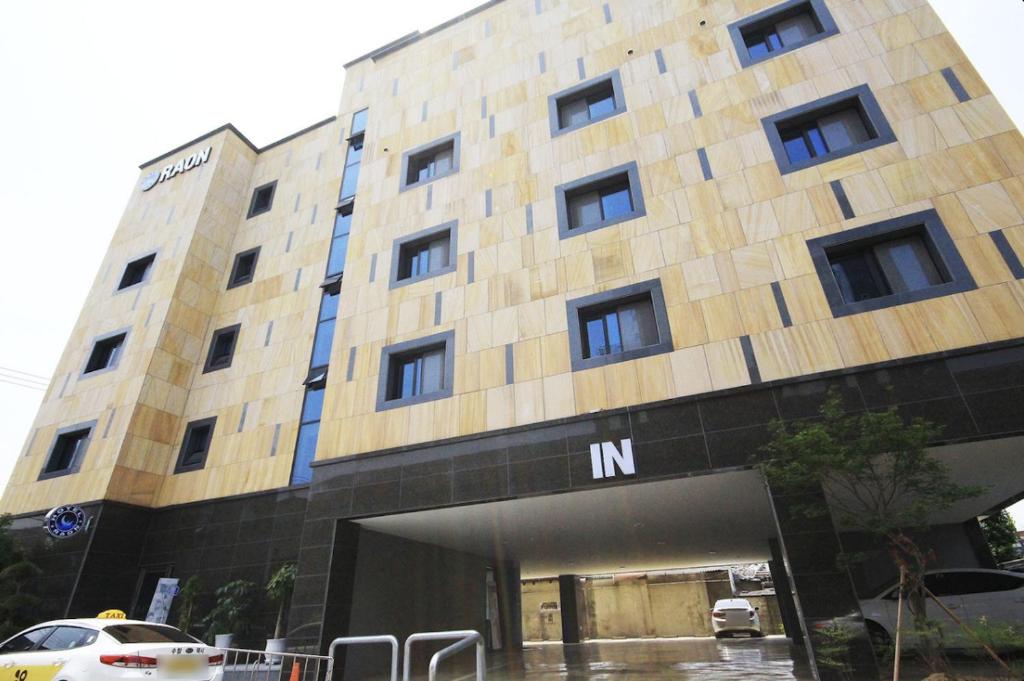 全州市にあるJeonju Raon Hotelの大きな建物で、目の前に駐車場があります。