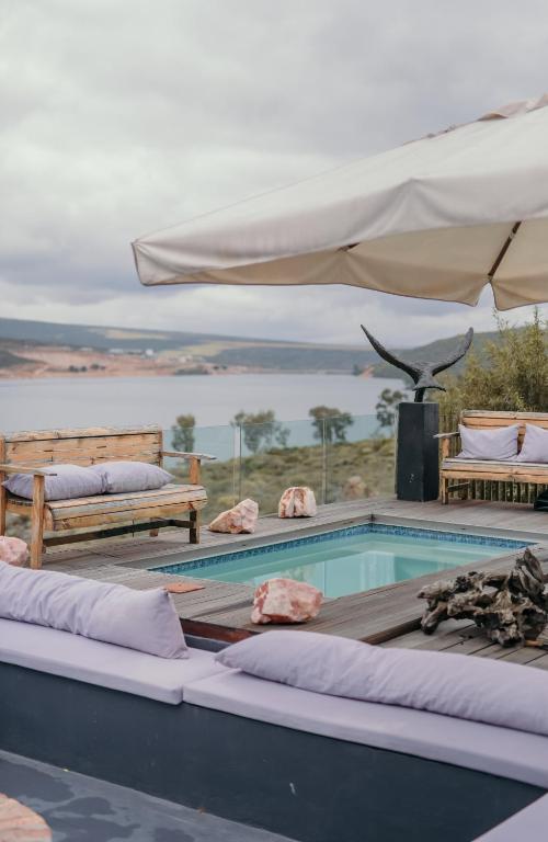 a swimming pool with two benches and an umbrella at Clanwilliam Dam House in Clanwilliam