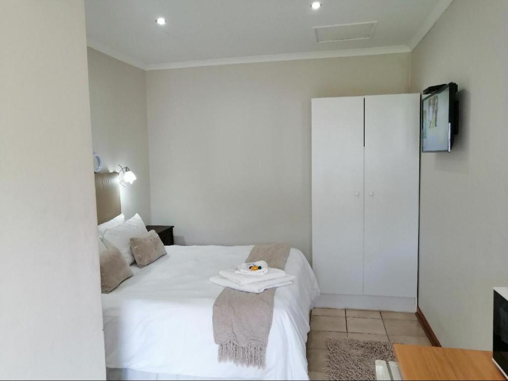 een slaapkamer met een wit bed en een tafel. bij Twilight Inn in Vryheid