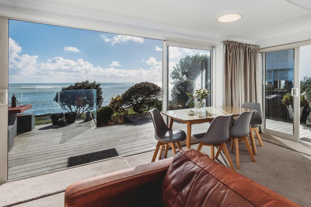 Una sala de estar con una mesa y vista al mar. en Te Moana Waterfront - beachside accommodation, en New Plymouth