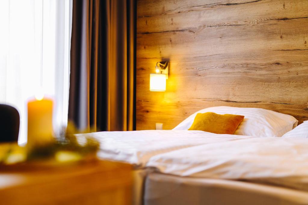 Un dormitorio con una cama con una pared de madera. en Hotel SKI, en Nové Město na Moravě