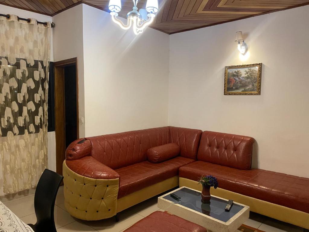 Una sala de estar con un sofá de cuero marrón y una mesa. en King's home, en Yaoundé