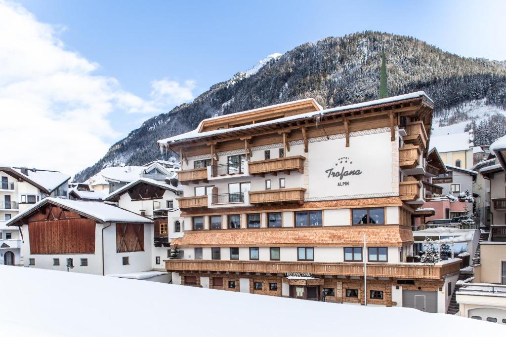 un edificio en la nieve con una montaña en el fondo en Hotel Trofana Alpin, en Ischgl