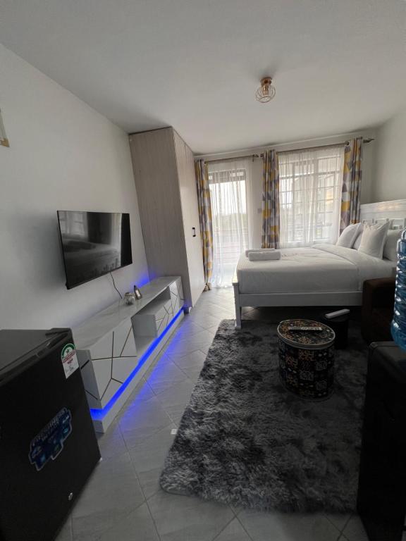 une chambre avec un lit, une télévision et un canapé dans l'établissement Anakwa Villas, à Nairobi