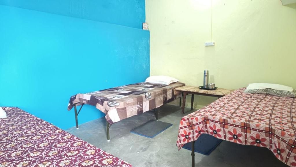 a room with two beds and a table in it at Himalayan 5 Elements Healing & Ayurveda in Narendranagar