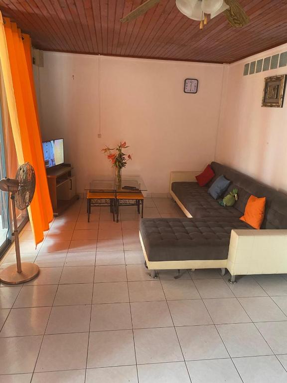 a living room with two beds and a table at Hébergement Maison -Les Abymes in Les Abymes