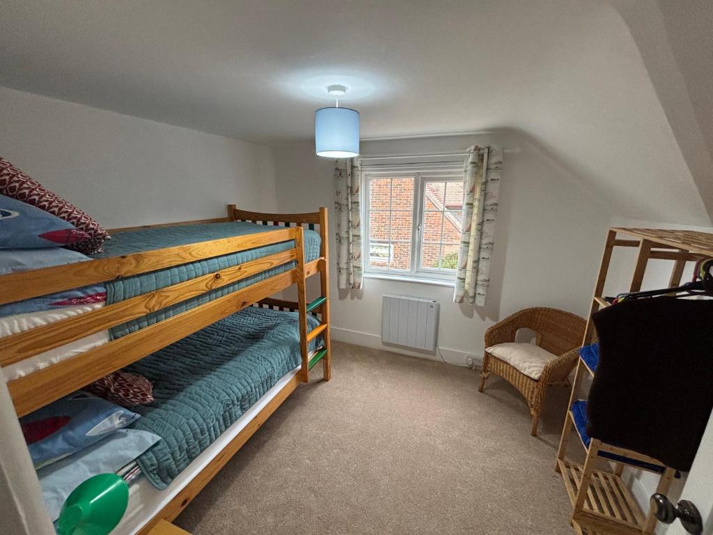 a bedroom with a bunk bed and a chair at Delightful 3-bedroom Cottage, Brockenhurst in Brockenhurst