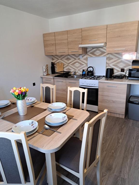 une cuisine avec une table en bois avec des assiettes et des chaises blanches dans l'établissement Pociechówka apartament, à Tylicz