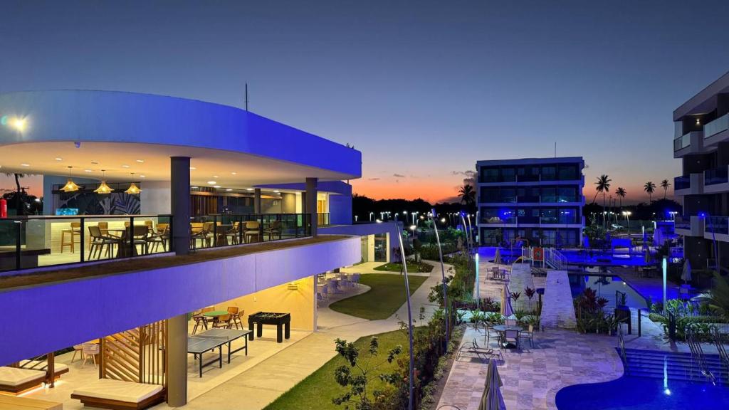 a view of a building with a pool at dusk at Makia Beach experience 107 D Premium in Ipojuca