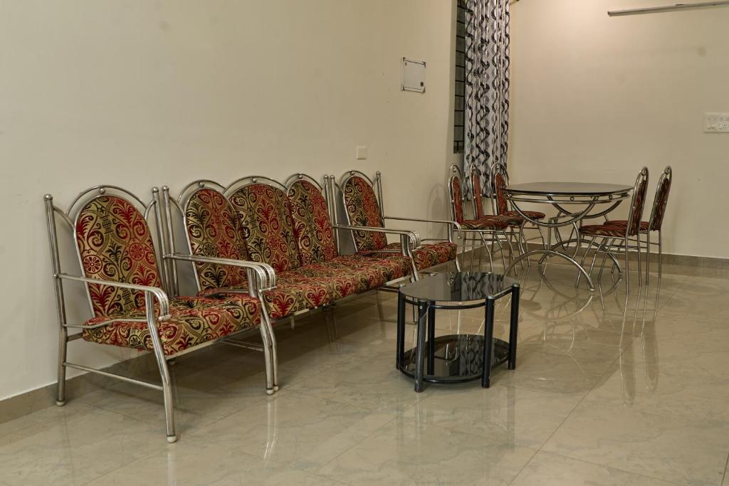 Immanuel Homestay, Kalathipady, Kottayam, Flat E في كوتايم: غرفة مع أريكة وطاولة مع كراسي