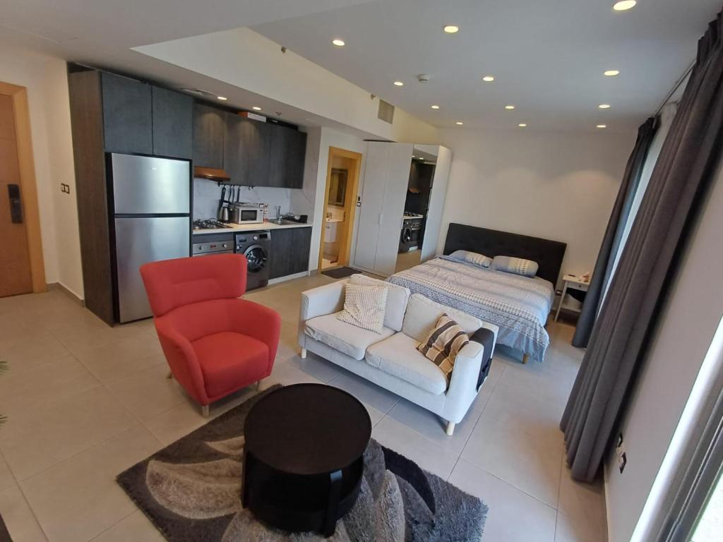 a living room with a bed and a red chair at Studio at Damak Jordan in Amman