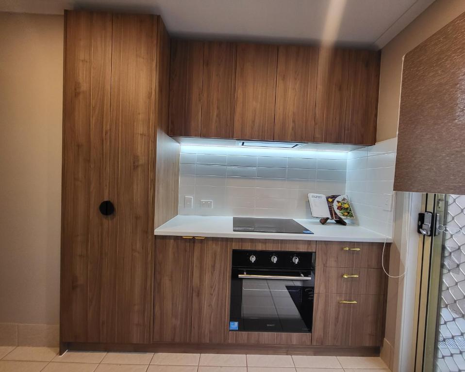 a kitchen with wooden cabinets and a stove top oven at Private Room 1- The Minimalist Escape in Craigieburn
