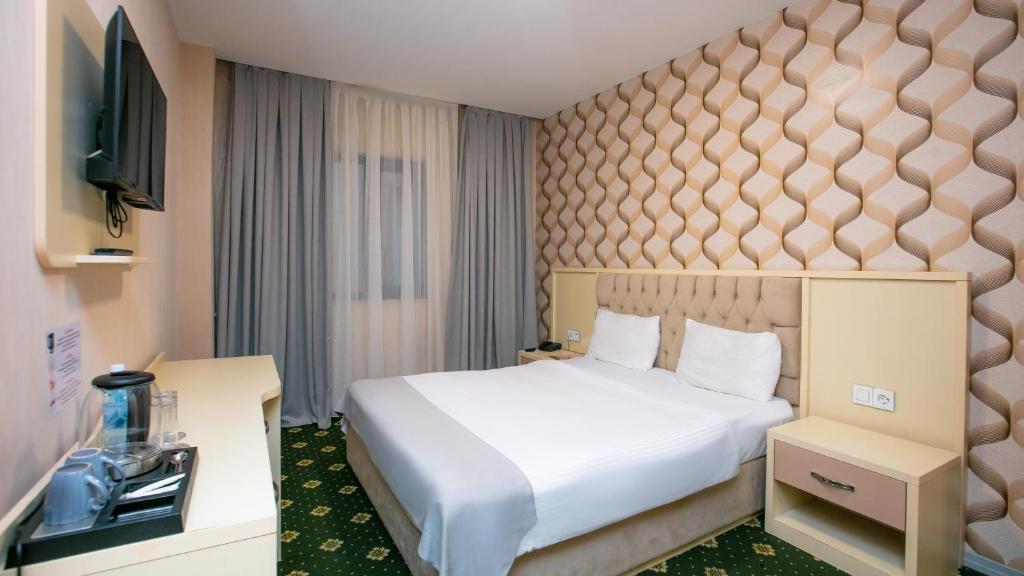a hotel room with a bed and a flat screen tv at Alis Business Hotel baku in Baku