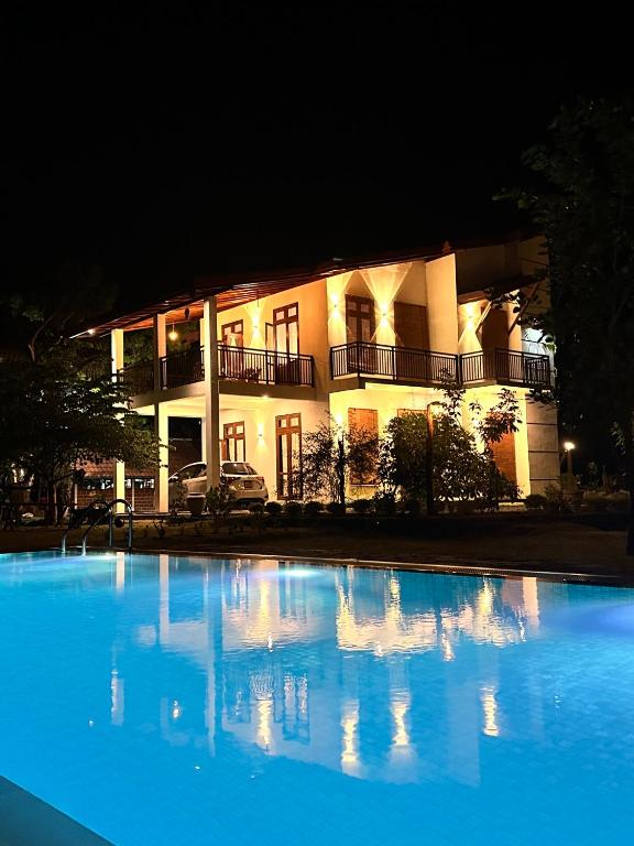 a large blue swimming pool in front of a building at Kadalla Holiday Resort in Rambukanagama