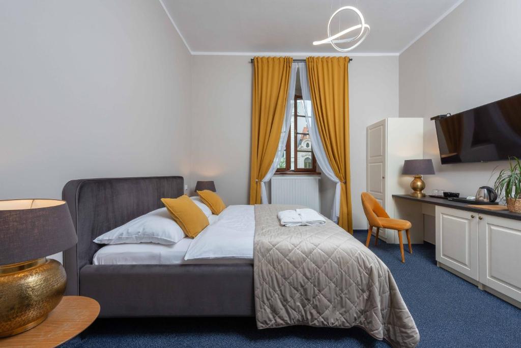 a bedroom with a bed with yellow pillows and a television at Zámecký hotel & Wellness in Poděbrady