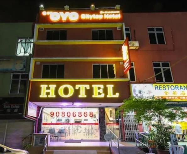 a hotel with neon signs in front of a building at Pillows Plus City Top in Cheras