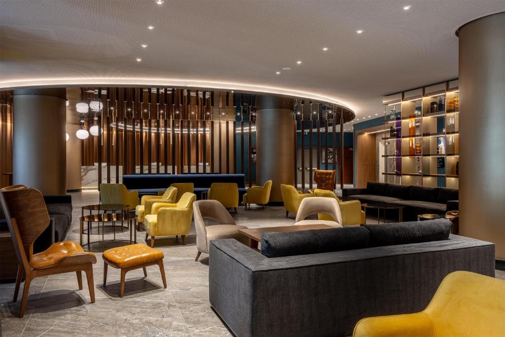 a lobby with yellow chairs and couches and tables at Radisson Blu Hotel, Florence in Florence