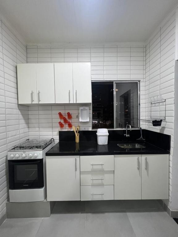 a kitchen with white cabinets and a black counter top at Casa de Mainha - Vila Mariana - unidade 1 in Sao Paulo