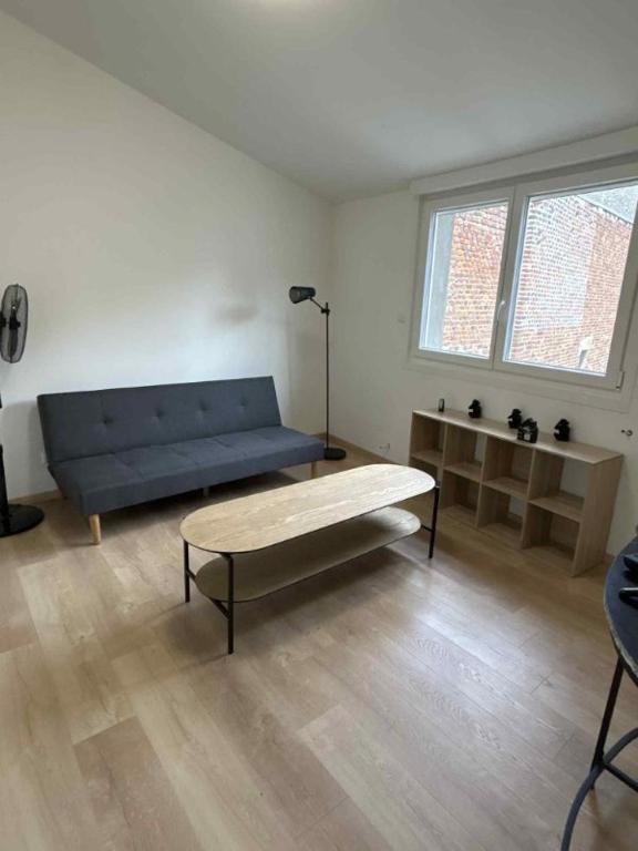 a living room with a blue couch and a table at Appartement Peronne Centre in Péronne