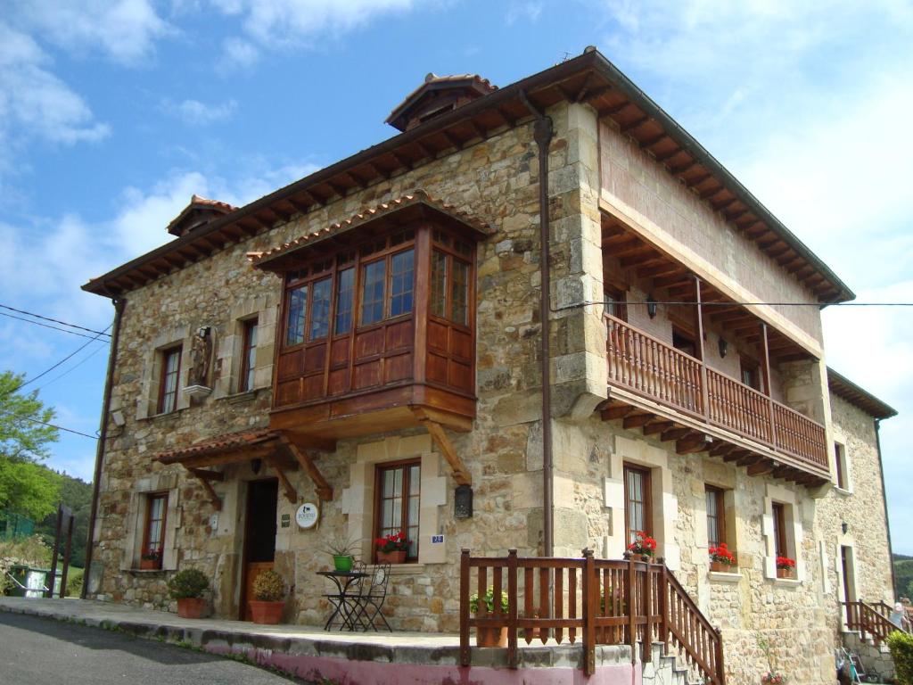 una casa de piedra con un balcón en un lateral. en Hotel Rural El Angel de la Guarda, en Güemes