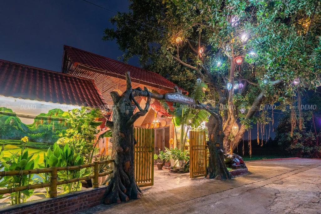 a house with a tree in front of a fence at TamCoc Moon An Bungalow & Cafe in Ninh Binh