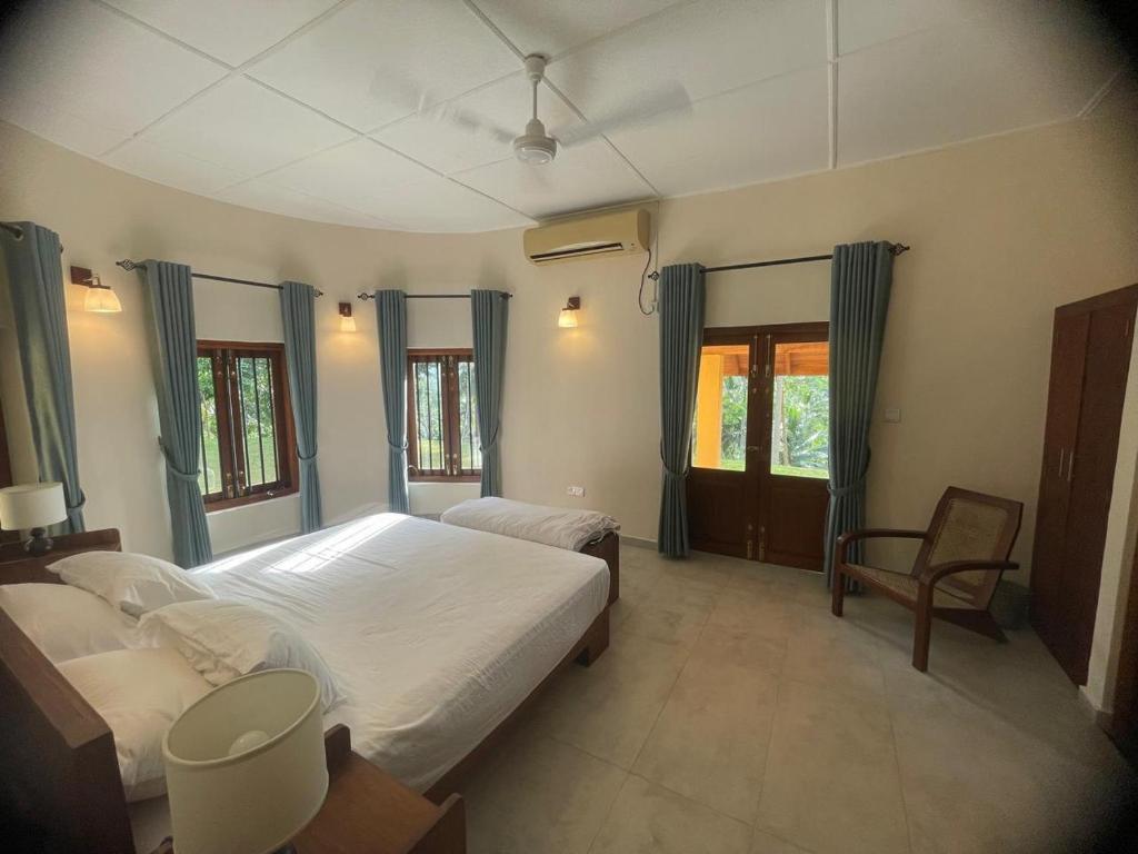 a bedroom with two beds and a chair at Sarangu VIlla in Akuressa