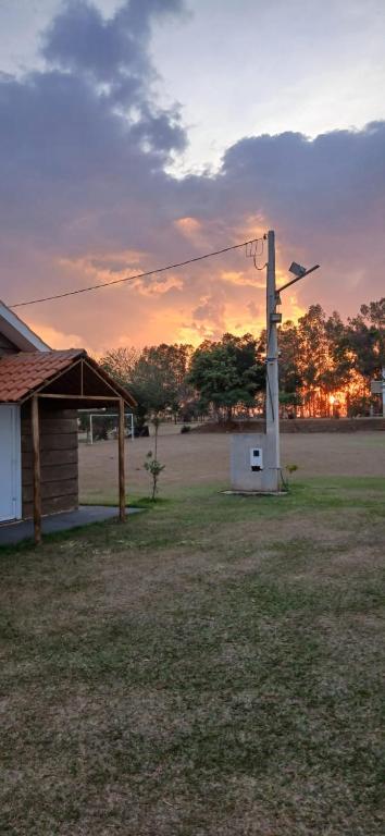 a wind turbine next to a house with a sunset at Chácara e Pousada Aeroporto in Andradina