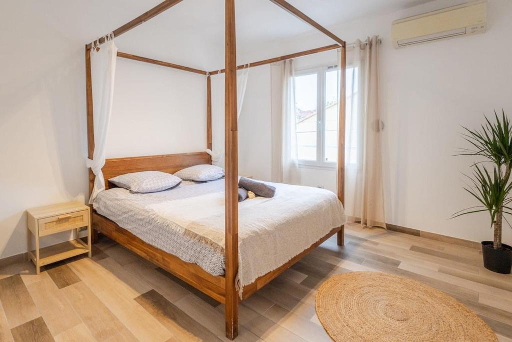 ein Schlafzimmer mit Himmelbett und Teppich in der Unterkunft Cosy de la Pointe Rouge - Terrasse - Port plage et commerces in Marseille