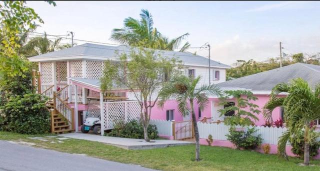 a pink house with palm trees in front of it at Tickled Pink in Harbour Island