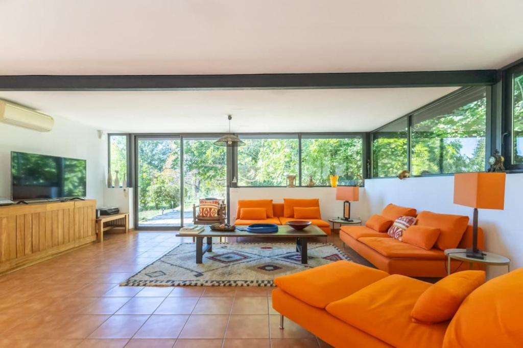 an open living room with orange furniture and windows at Villa Wagner - Aix en Provence in Les Platrières
