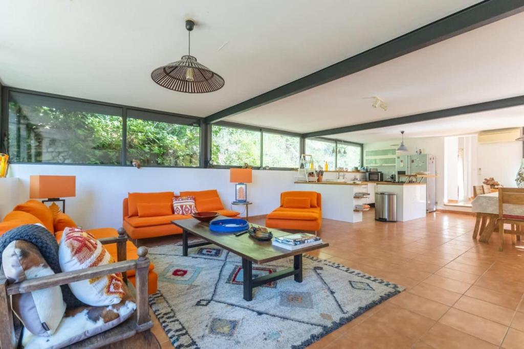 Villa sur Domaine Aix - Piscine & Tennis - Wagner في Les Platrières: غرفة معيشة مع كراسي برتقالية وطاولة