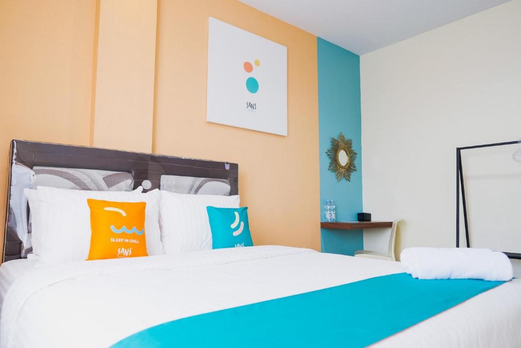 una camera da letto con un letto grande con cuscini colorati di Sans Hotel Cemara Asri Medan a Pulauberayan Dadap
