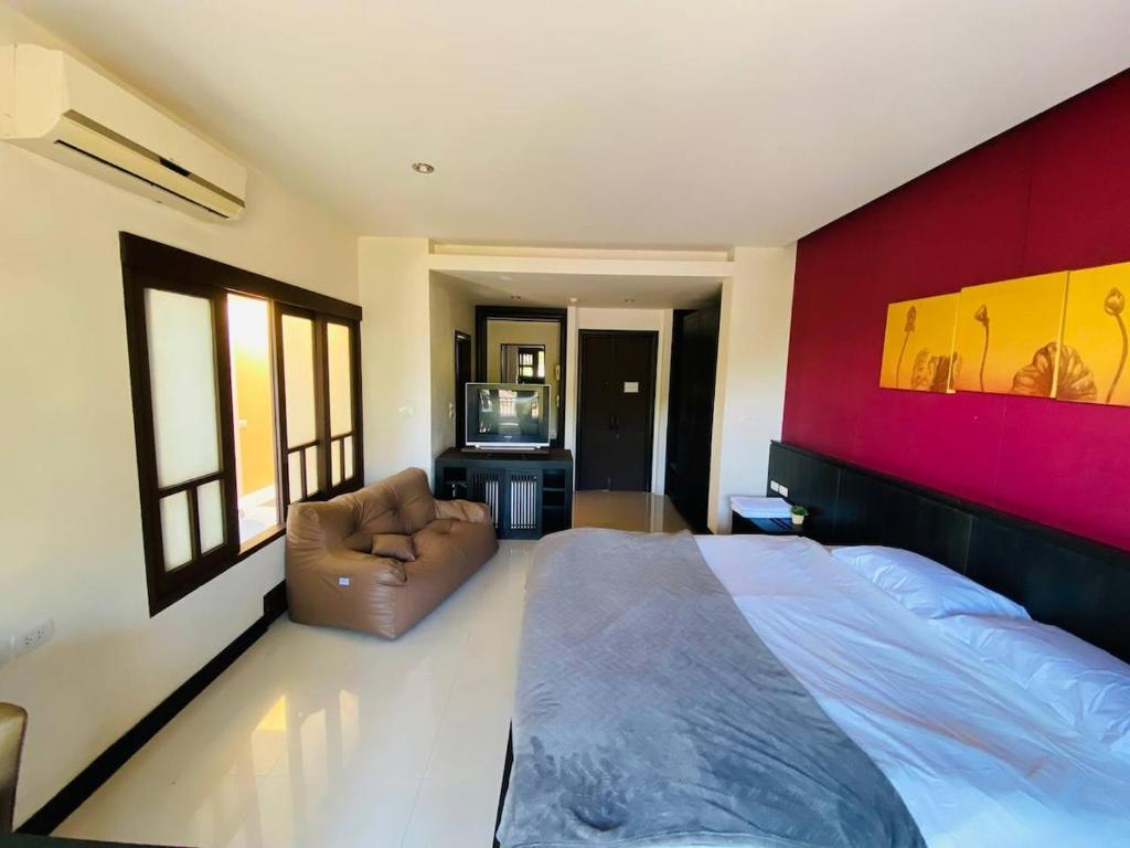 a bedroom with a large bed and a chair at Sea top room in Amphoe Koh Samui