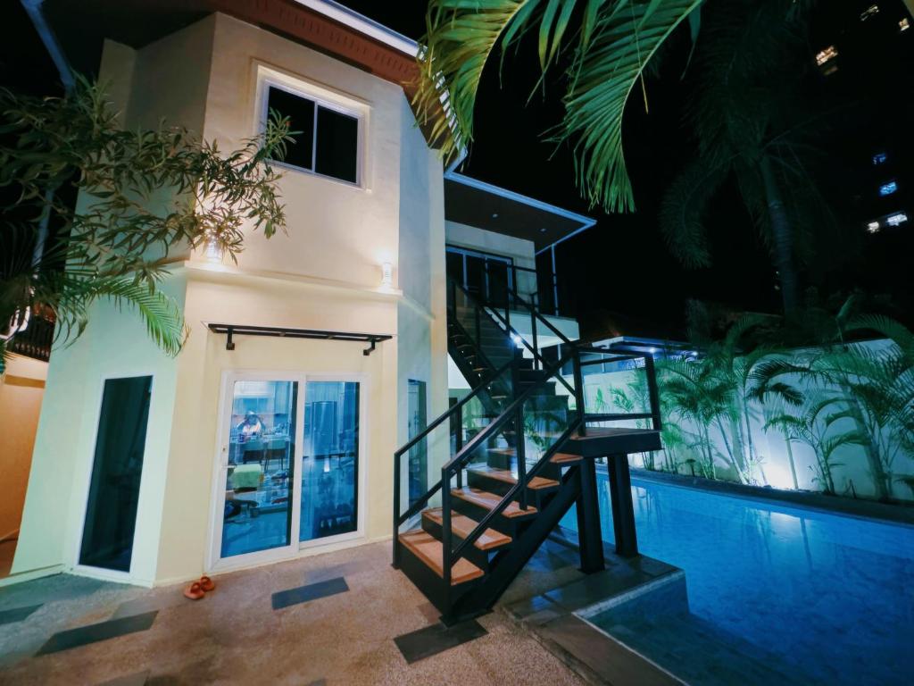a house with a staircase next to a swimming pool at 3BR Pool Villa Beach Access Patumnak Hill in Pattaya South