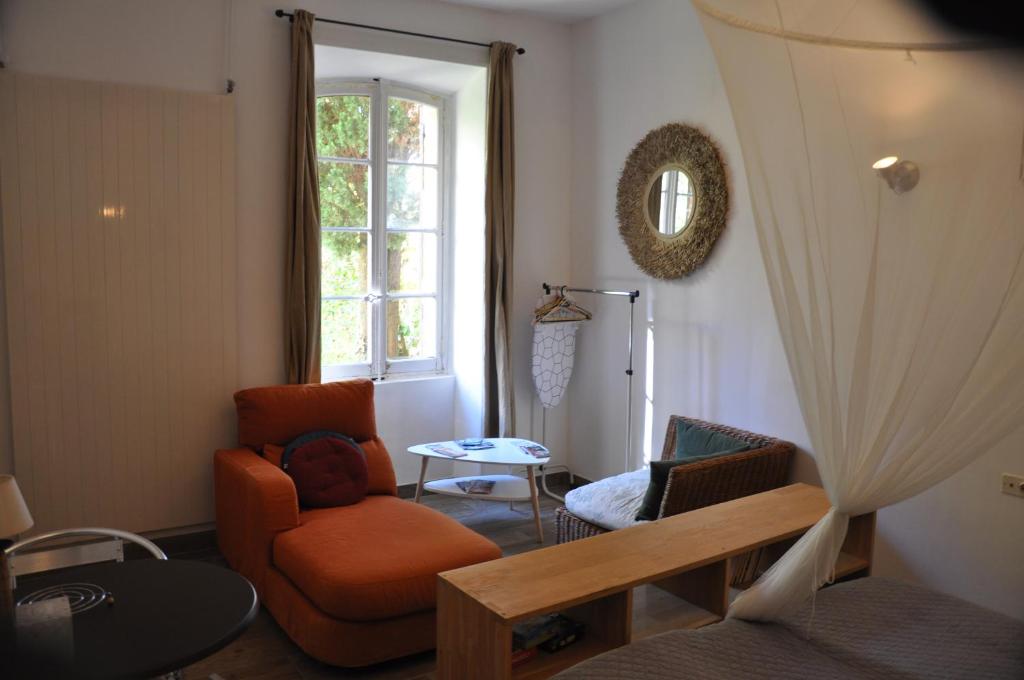 a living room with an orange chair and a window at location studio meublé avec jardin in Sorgues