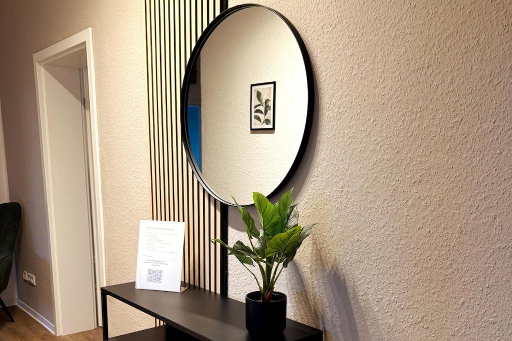 ein Spiegel an einer Wand neben einem Tisch mit einer Pflanze in der Unterkunft Urban Home in Hannover