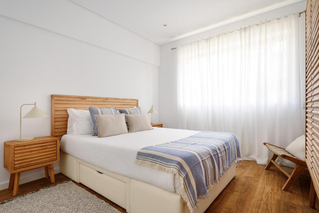 a white bedroom with a large bed and a window at Home on Rua da Alegria in Bicas