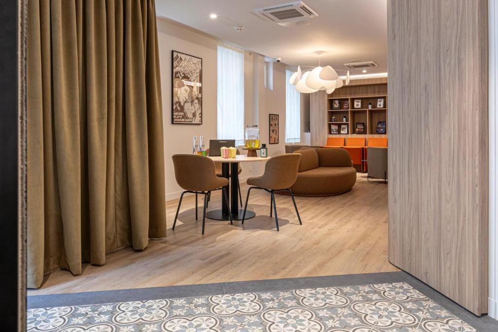 ブローニュ・ビヤンクールにあるDantan Hôtelのテーブルと椅子とソファのあるリビングルーム