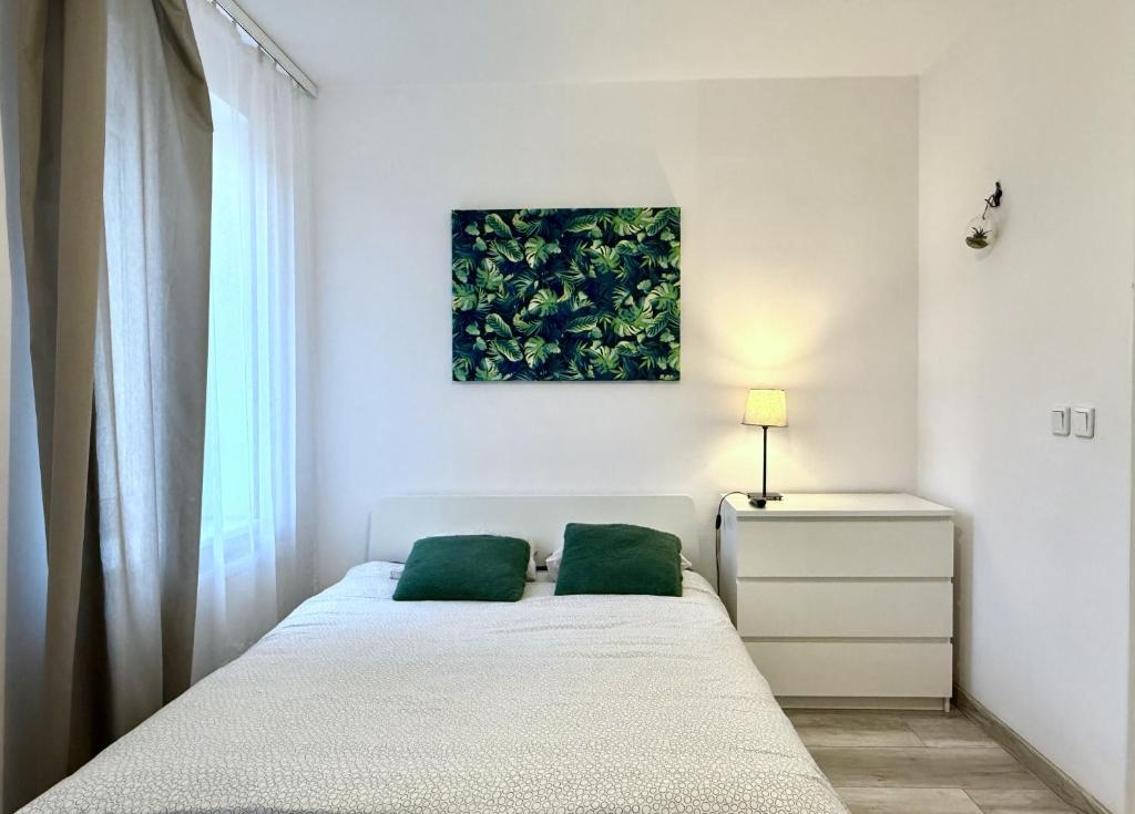 een slaapkamer met een bed en een schilderij aan de muur bij theApartments Manufaktura in Łódź