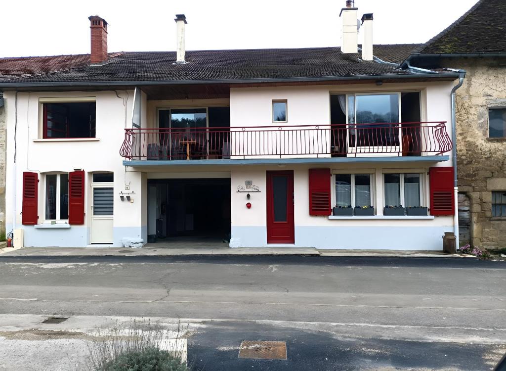 a white house with red doors and a balcony at Appartement Détente in Chamole