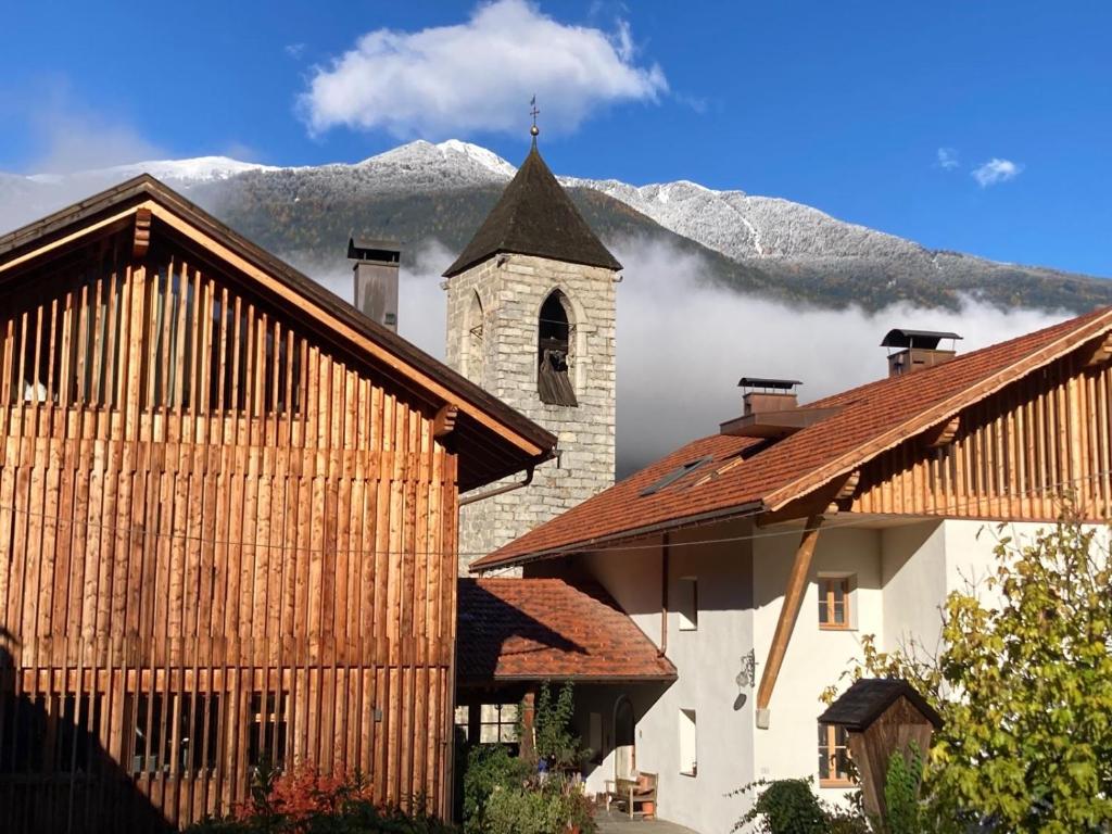 Un edificio con una iglesia con una montaña al fondo. en Kircherhof, en Bresanona