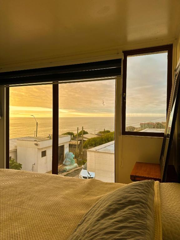 Un dormitorio con un gran ventanal con vista al mar. en Cabañas del Sol, en La Boca