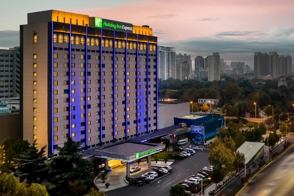 a hotel building with a parking lot in front of a city at Holiday Inn Express Zhengzhou Zhongzhou by IHG in Zhengzhou
