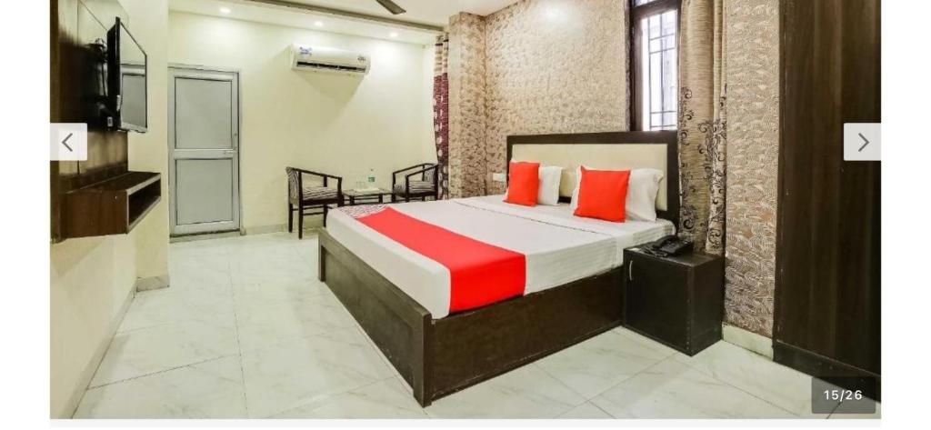 a bedroom with a bed with red pillows and a television at Hotel O Alpine in Chandīgarh