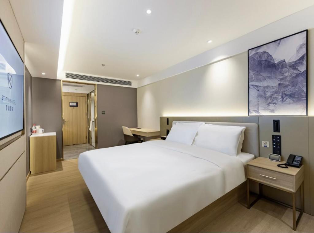 a bedroom with a large white bed and a television at Xingcheng Beijing Huilongguan Jishuitan Hospital Hotel in Beijing