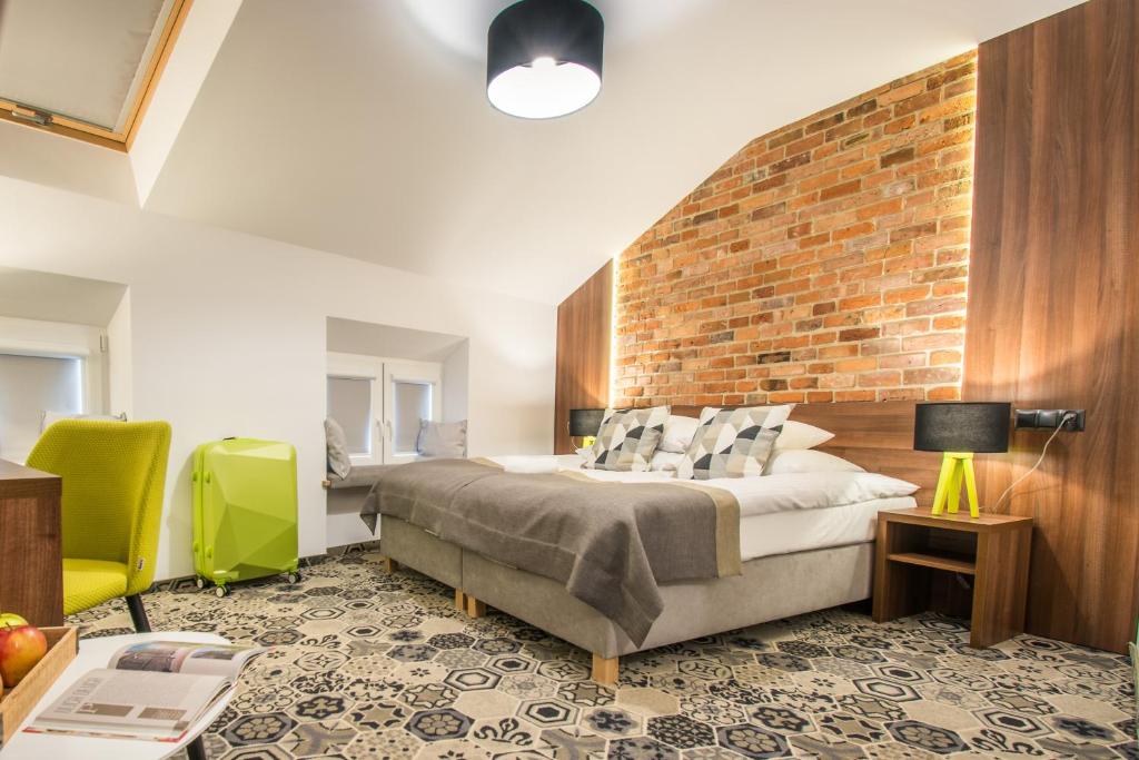 a bedroom with a bed and a brick wall at Hotel Lavender in Kraków