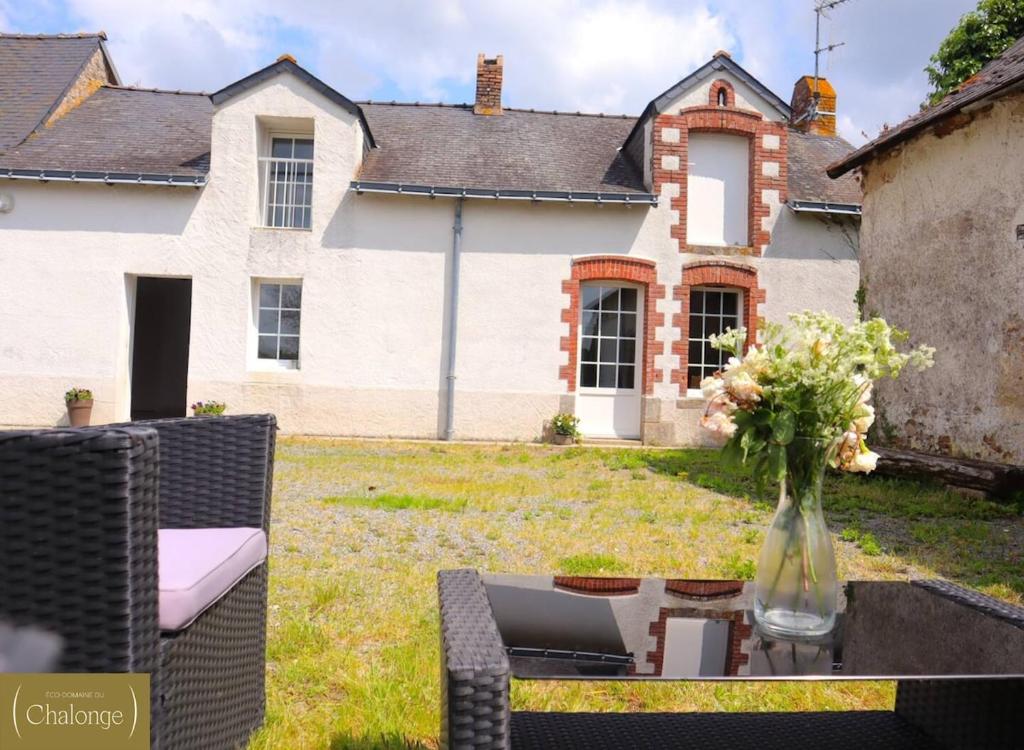 eine Vase mit Blumen auf einem Tisch vor einem Haus in der Unterkunft Cottage Cèdres - Maison chaleureuse à la campagne avec jardin in Héric