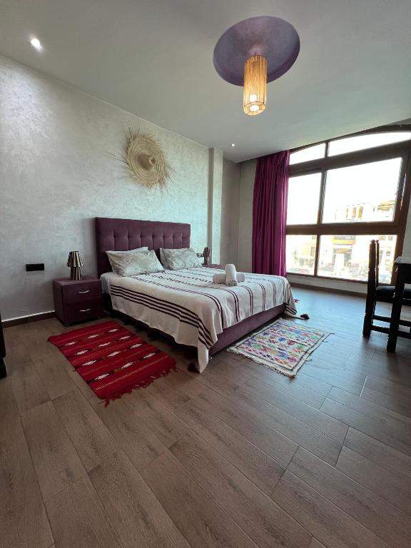 a bedroom with a large bed and a red rug at Nomad Surf Hotel in Tamraght Ouzdar