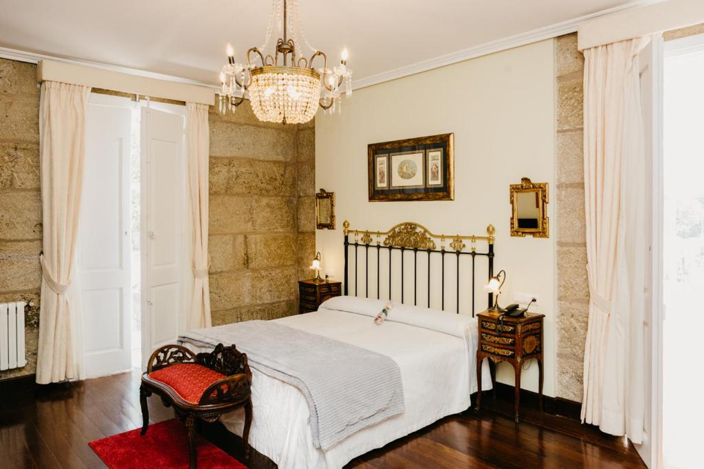 a bedroom with a white bed and a chandelier at Pazo Almuzara in Boborás