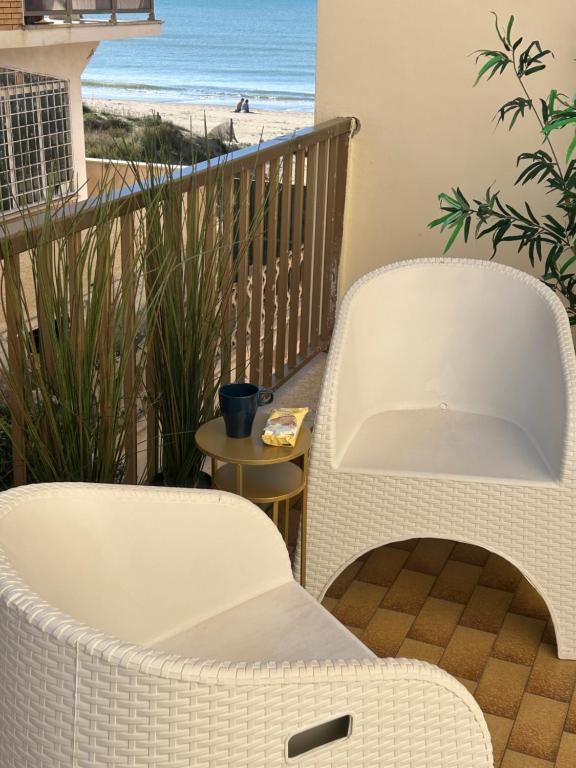 a balcony with two chairs and a view of the beach at Seaside two-room apartment in Torvaianica